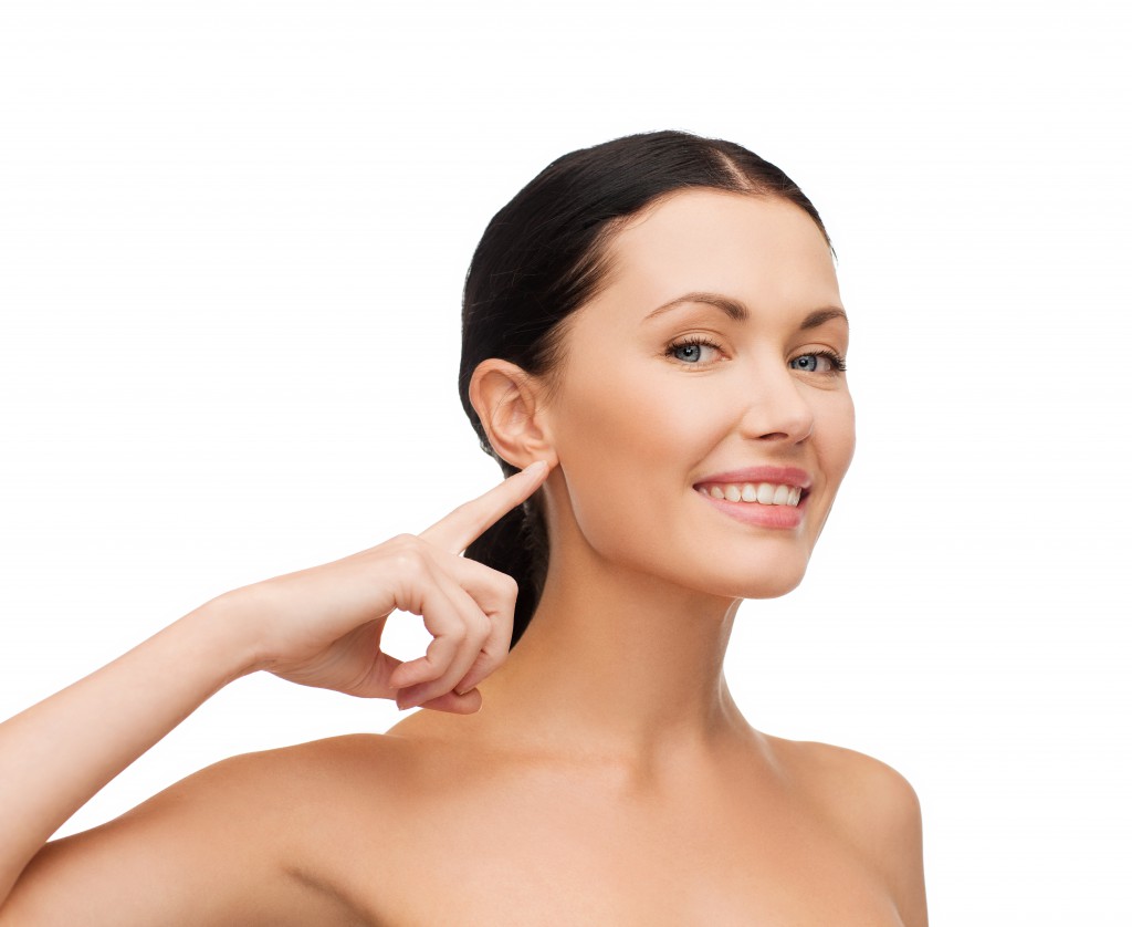 health, spa and beauty concept - clean face of beautiful young woman pointing to her ear